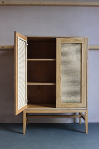 Mid-century style rattan cane cabinet featuring oak veneered plywood, solid oak legs and woven cane in-lay. Designed and made by Jon Grant London in Leyton, East London.