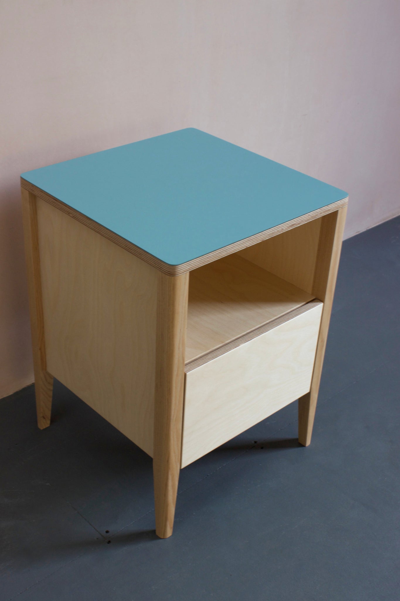 Handmade bedside table, perfect for a modern home. It features Forbo lino top with plywood carcass and solid ash legs. Made by Jon Grant London in Leyton, East London.