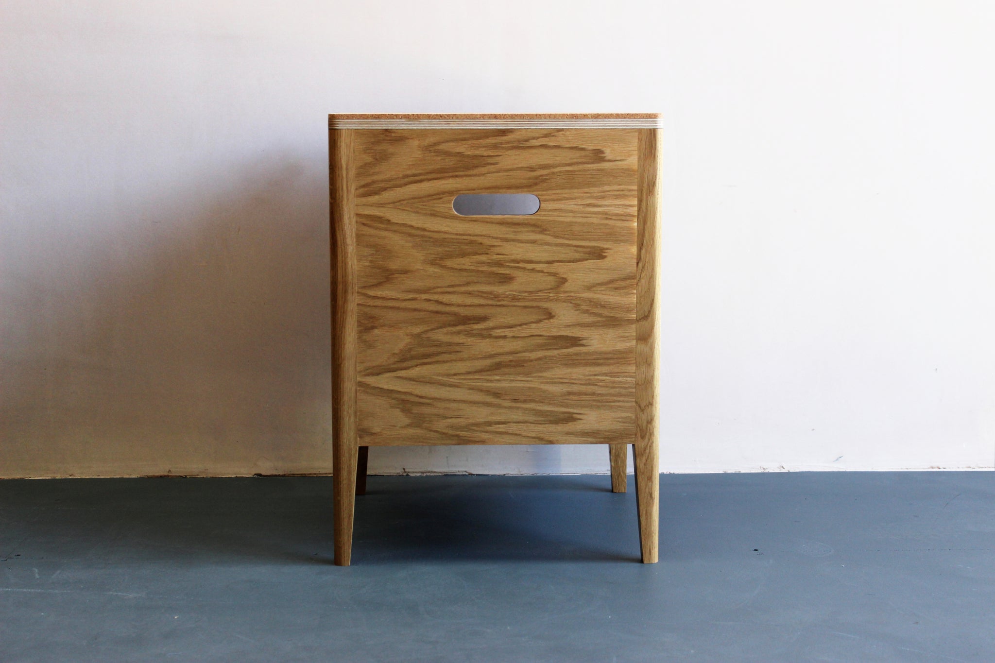 Handmade bedside table, perfect for a modern home. It features cork top with oak veneered plywood and solid oak legs. Made by Jon Grant London in Leyton, East London.